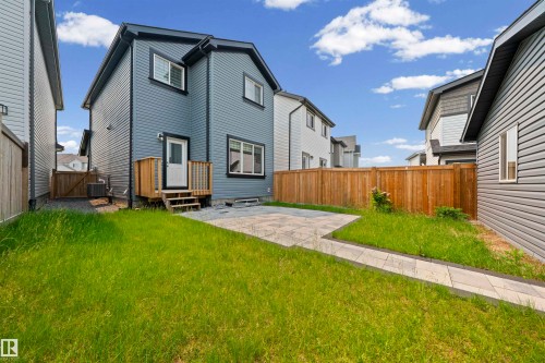 Rear exterior featuring gray horizontal siding, a wooden deck with stairs, a paver patio, and a wooden privacy fence - 2953 Coughlan Green Green, Edmonton, AB 