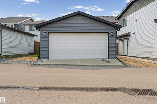Detached two-car garage with horizontal siding, a gabled roof, and exterior lighting fixtures - 2953 Coughlan Green Green, Edmonton, AB 
