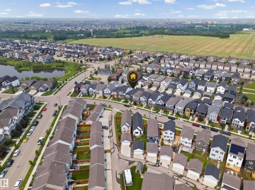 Aerial perspective showcasing a residential development with diverse architectural styles, featuring a prominent pond and open fields - 2953 Coughlan Green Green, Edmonton, AB 