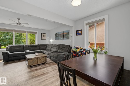 Open-concept living space featuring wood-finish flooring, a contemporary ceiling fan, and large windows providing abundant natural light - 3622 115 Avenue, Edmonton, AB 