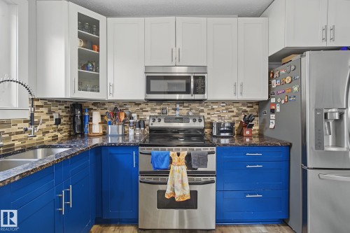 Kitchen featuring two-tone cabinetry with bright blue base cabinets and white upper cabinets - 3622 115 Avenue, Edmonton, AB 