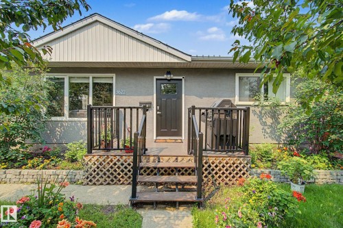 Front exterior featuring a dark entry door, white trim, and a small elevated deck with black railings - 3622 115 Avenue, Edmonton, AB 