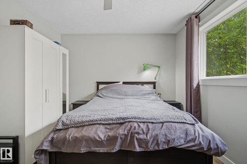 Spacious bedroom featuring light grey walls, a white ceiling fan, and a large window with white trim - 3622 115 Avenue, Edmonton, AB 