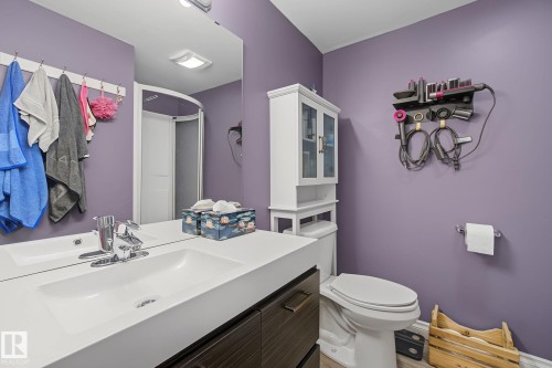 Bathroom featuring a single vanity with an integrated sink, chrome faucet, and dark wood-finish cabinetry - 3622 115 Avenue, Edmonton, AB 