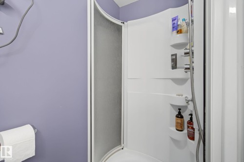 Shower enclosure with curved glass door, white composite shower surround, chrome fixtures, and integrated shelving - 3622 115 Avenue, Edmonton, AB 