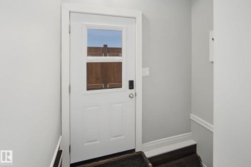 White paneled door featuring an upper window, a contemporary black digital lock, and a satin nickel knob - 3622 115 Avenue, Edmonton, AB 