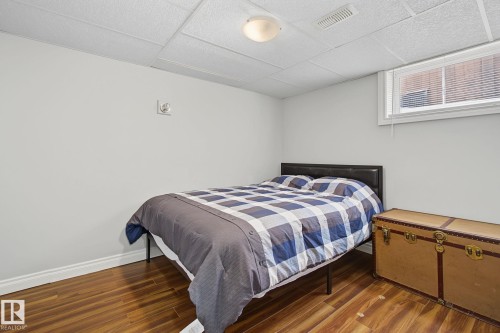 Bedroom featuring a window, wood-finish flooring, light gray walls, white trim, and a drop ceiling with recessed lighting - 3622 115 Avenue, Edmonton, AB 