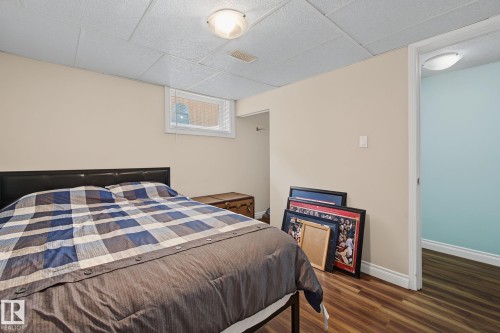 Spacious room featuring neutral wall paint, wood-finish flooring, a drop ceiling, and a single window - 3622 115 Avenue, Edmonton, AB 