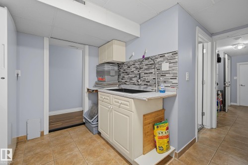 Built-in utility sink with a mosaic tile backsplash and a single-handle pull-down faucet - 3622 115 Avenue, Edmonton, AB 