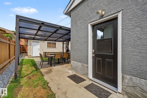Covered patio area with concrete surfacing, bordered by a wooden privacy fence and gravel landscaping - 3622 115 Avenue, Edmonton, AB 