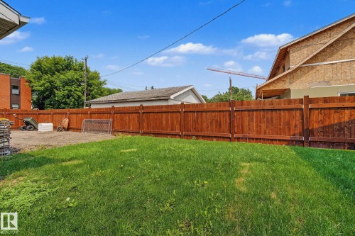 Expansive backyard featuring a lush green lawn, full wood privacy fencing, and a gravel area - 3622 115 Avenue, Edmonton, AB 