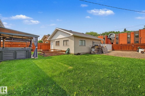 Spacious green lawn featuring a privacy fence, a detached auxiliary building, and a dedicated garden bed - 3622 115 Avenue, Edmonton, AB 