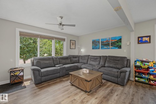 Living area with wood-finish flooring, a large window with blinds, and light-toned wall paint - 3622 115 Avenue, Edmonton, AB 