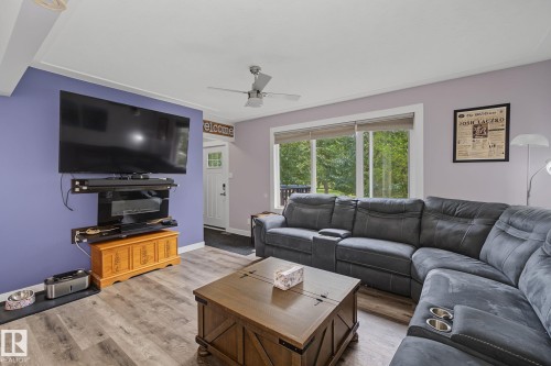 Spacious living area featuring wood-finish flooring, a ceiling fan, and a large window - 3622 115 Avenue, Edmonton, AB 