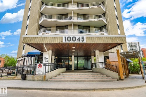 Building exterior featuring a covered entryway with wood-finish ceiling, concrete steps, and a ramp with black metal railings - 503 10045 117 Street, Edmonton, AB 