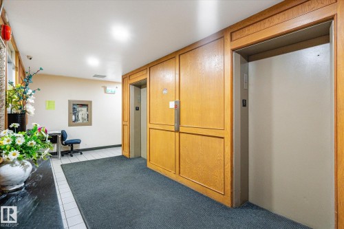 Dual elevator access featuring wood-paneled surrounds and brushed metal doors - 503 10045 117 Street, Edmonton, AB 