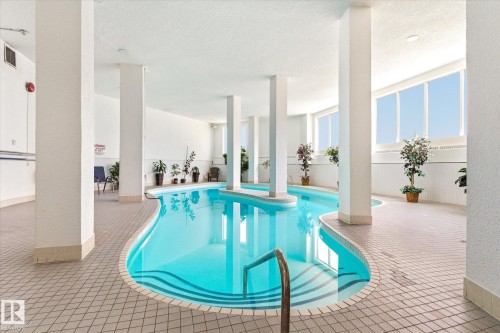 Indoor swimming pool featuring a serpentine design, integrated stairs, and a metal handrail - 503 10045 117 Street, Edmonton, AB 