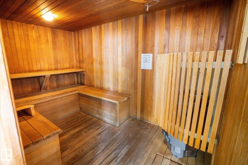 Private sauna featuring extensive wood paneling, built-in benches, wood-finish flooring, and a protected heating element - 503 10045 117 Street, Edmonton, AB 
