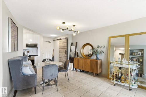 Open-concept living area with tile flooring and a modern linear chandelier - 503 10045 117 Street, Edmonton, AB 