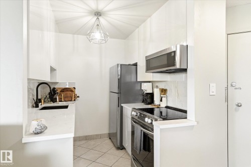 Modern kitchen featuring white cabinetry and stainless steel appliances - 503 10045 117 Street, Edmonton, AB 