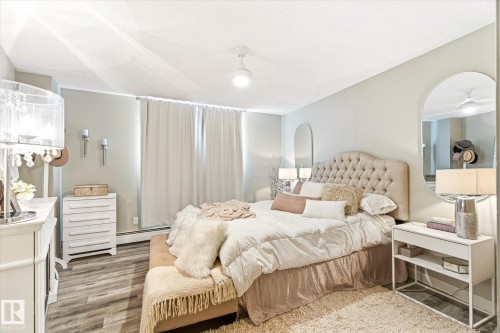 Bedroom featuring wood-finish flooring, a tufted headboard, and light-toned walls - 503 10045 117 Street, Edmonton, AB 