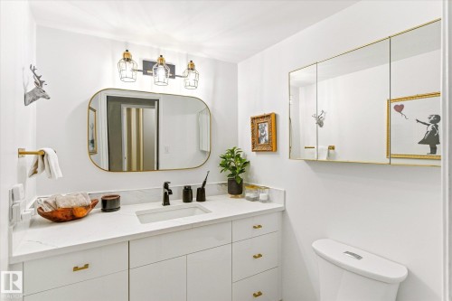 Modern bathroom featuring a white vanity with gold hardware, a white countertop, and an undermount sink - 503 10045 117 Street, Edmonton, AB 
