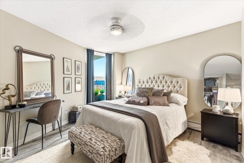 Spacious room featuring wood-finish flooring, a contemporary ceiling fan, and a built-in closet with shelving - 503 10045 117 Street, Edmonton, AB 
