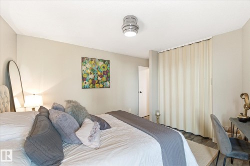 Neutral-toned bedroom featuring light grey walls and wood-finish flooring - 503 10045 117 Street, Edmonton, AB 