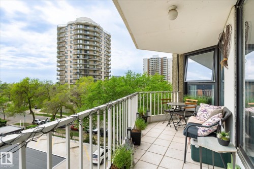 Balcony with a tiled floor, white metal railing, and a partial building facade - 503 10045 117 Street, Edmonton, AB 