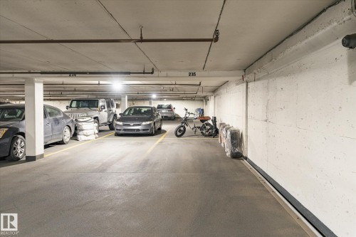 Underground parking garage featuring concrete walls, a concrete ceiling, and fluorescent lighting - 503 10045 117 Street, Edmonton, AB 