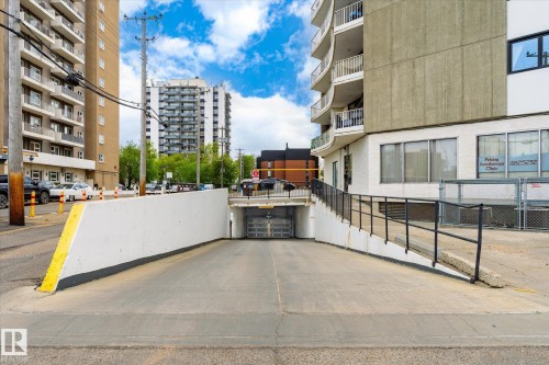 Concrete entrance ramp to an underground parking garage with a black metal handrail - 503 10045 117 Street, Edmonton, AB 