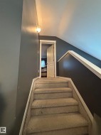 Carpeted stairway with white trim and a wall-mounted light fixture - 