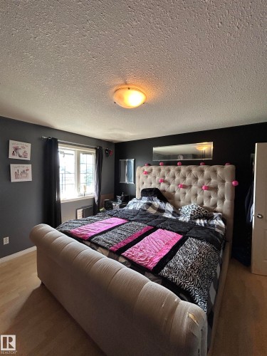 Spacious room featuring wood-finish flooring, a window with dark curtain rods, and dark wall paint - 17 Willowby Close, Stony Plain, AB 
