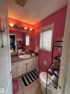 Bathroom featuring a single vanity with white cabinetry, an integrated sink, and a laminate countertop - 