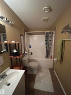 Bathroom featuring a vanity with an integrated sink, a commode, and a tub/shower combination with a white surround - 