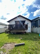 Rear exterior featuring a spacious wooden deck with railings and steps - 