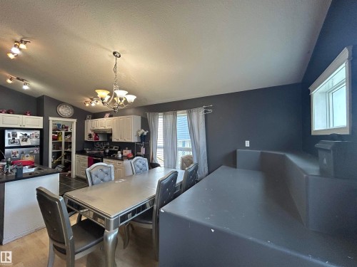 Open-concept kitchen and dining area featuring white cabinetry, dark countertops, a vaulted ceiling, wood-finish flooring, and track lighting - 17 Willowby Close, Stony Plain, AB 