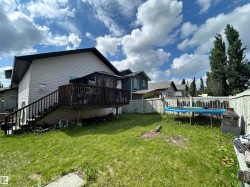 Expansive backyard featuring a wood privacy fence, a multi-level wood deck with railings, and a sheltered outdoor space - 
