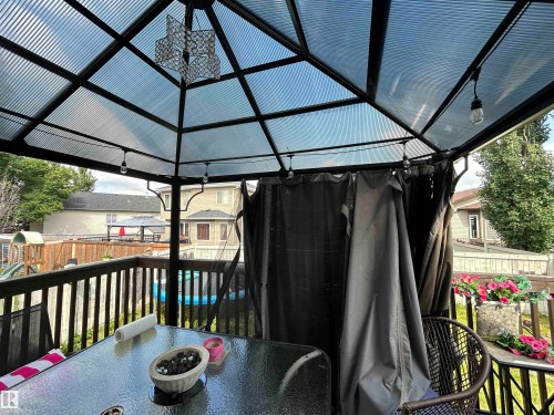 Deck area featuring a gazebo with a corrugated translucent roof, integrated lighting, and privacy curtains - 17 Willowby Close, Stony Plain, AB 