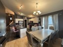 Open-concept living space with a kitchen island, white cabinetry, and dark-finish countertops - 17 Willowby Close, Stony Plain, AB 