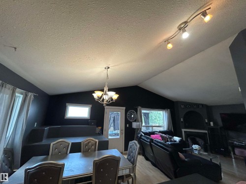 Vaulted ceiling with track lighting and a chandelier, wood-finish flooring, and a built-in tiered platform - 17 Willowby Close, Stony Plain, AB 
