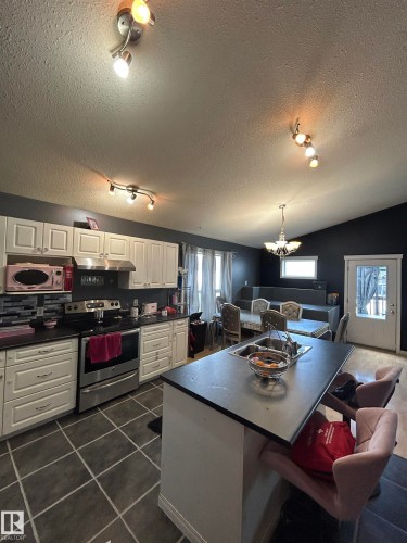 Open-concept kitchen featuring white cabinetry, stainless steel appliances, and dark countertops - 17 Willowby Close, Stony Plain, AB 