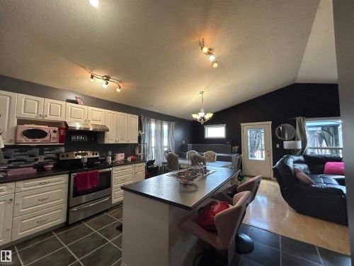 Open-concept kitchen with white cabinetry, stainless steel appliances, and dark countertops - 17 Willowby Close, Stony Plain, AB 