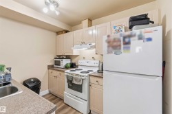 Kitchen featuring light wood-finish cabinetry, speckled countertops, stainless steel sink, and wood-finish flooring - 