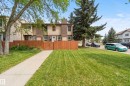 Two-story townhouse with a brown and tan exterior, featuring a wood fence, a concrete walkway, and a spacious front lawn - 17118 108 Street, Edmonton, AB 