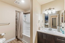 Bathroom featuring a shower-tub combination with tile surround, a single vanity with a dark wood-finish cabinet, and a large mirror - 