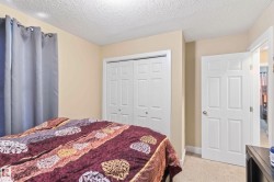 Carpeted bedroom featuring neutral wall tones, white bi-fold closet doors, a white paneled interior door, recessed lighting, and a textured ceiling - 
