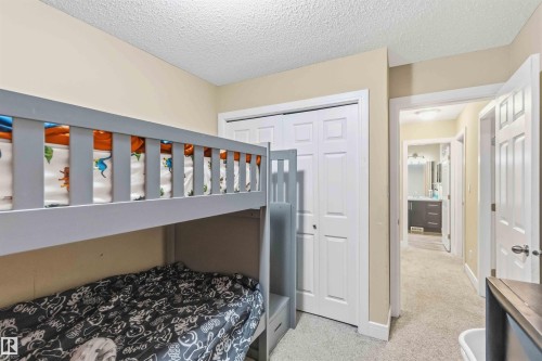 Bedroom featuring neutral wall paint, textured ceiling, light-toned carpet, and a white bi-fold closet - 17118 108 Street, Edmonton, AB 