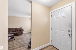Entryway featuring a paneled door with an arched transom window, wood-finish flooring, and light-toned walls - 
