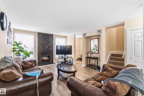 Living area featuring wood-finish flooring, a stone-clad fireplace, and two windows - 17118 108 Street, Edmonton, AB 